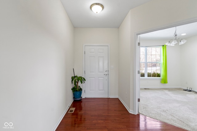 interior space with baseboards, visible vents, an inviting chandelier, and wood finished floors