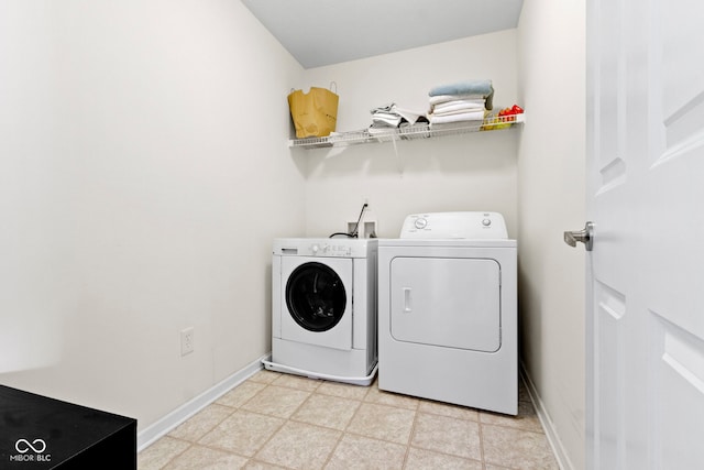 clothes washing area with light floors, washer and dryer, laundry area, and baseboards