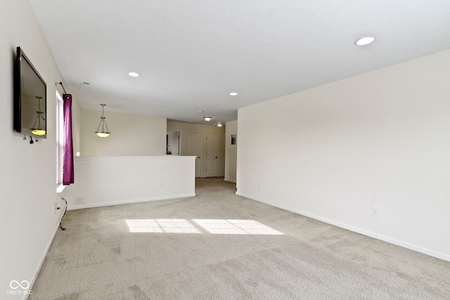 empty room featuring recessed lighting, light carpet, and baseboards