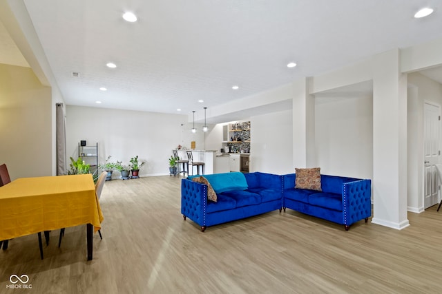 living room featuring bar, baseboards, wood finished floors, and recessed lighting