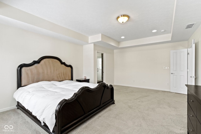 bedroom featuring light carpet, visible vents, baseboards, and a tray ceiling