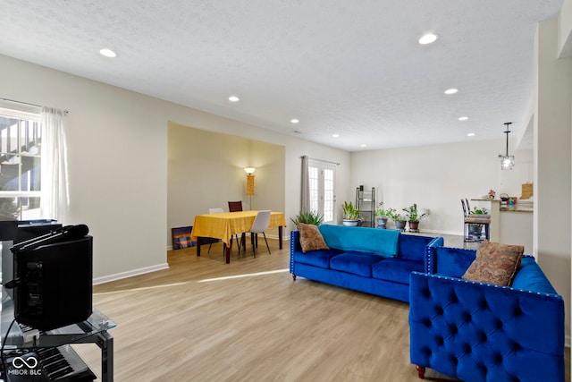 living room with light wood-type flooring, a textured ceiling, baseboards, and recessed lighting