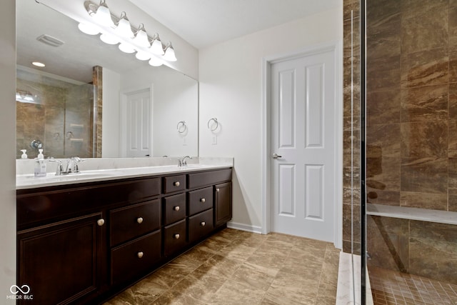 bathroom featuring tiled shower, a sink, baseboards, and double vanity