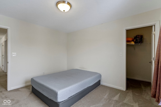 bedroom featuring a closet, carpet, a walk in closet, and baseboards