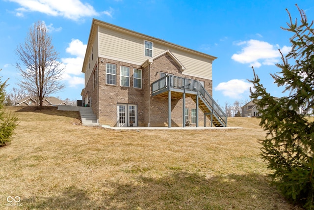 rear view of house with french doors, brick siding, a yard, a wooden deck, and stairs