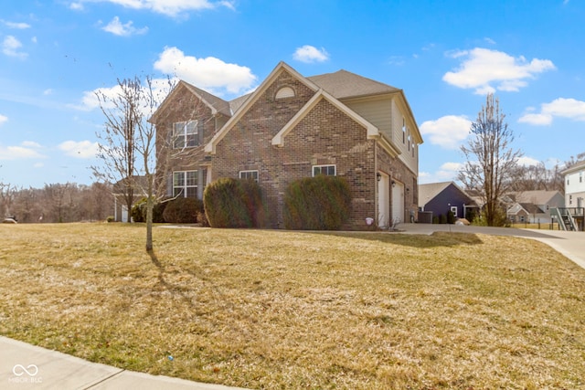 view of front of house with driveway, brick siding, an attached garage, and a front yard