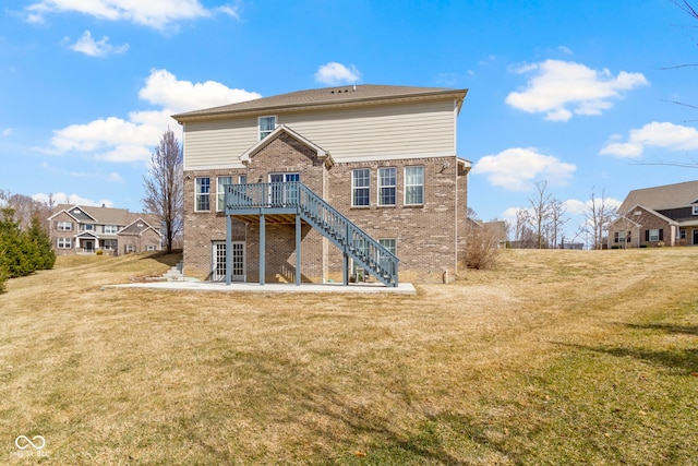 back of house featuring stairs, brick siding, a lawn, and a deck