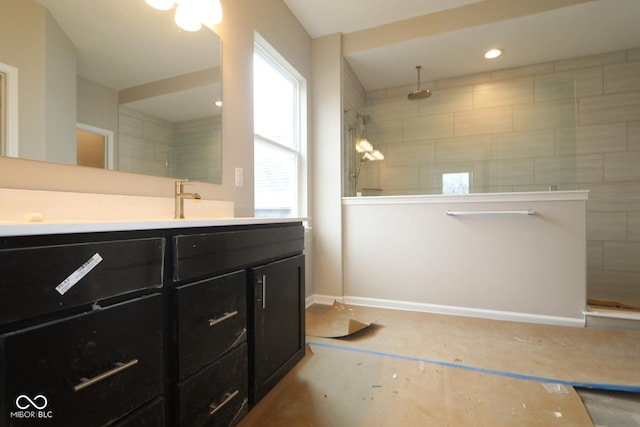 bathroom with tiled shower and vanity