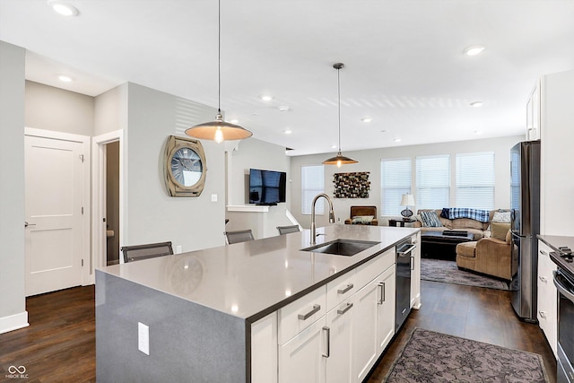 kitchen featuring hanging light fixtures, appliances with stainless steel finishes, sink, white cabinets, and a kitchen island with sink