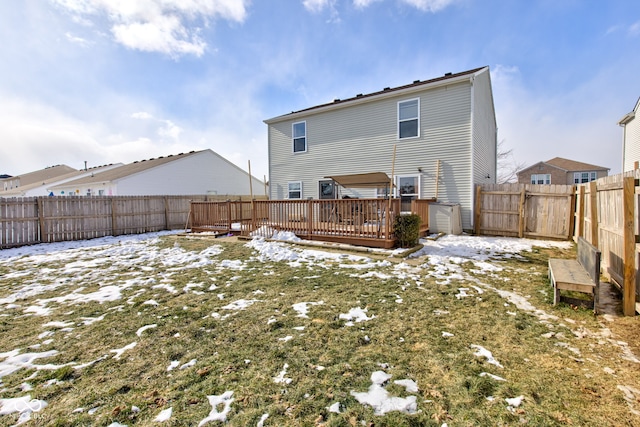 snow covered back of property with a wooden deck