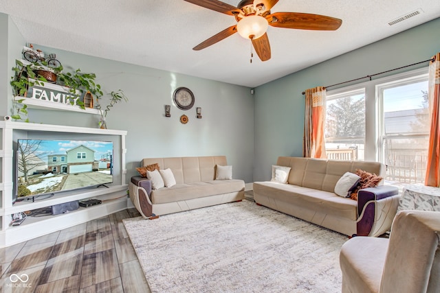 living room featuring ceiling fan, wood-type flooring, and a textured ceiling