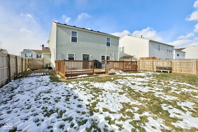 snow covered back of property with a wooden deck