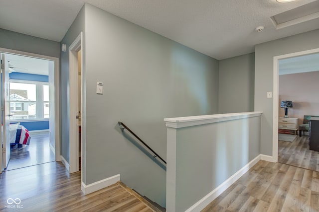 hallway with a textured ceiling and light hardwood / wood-style flooring