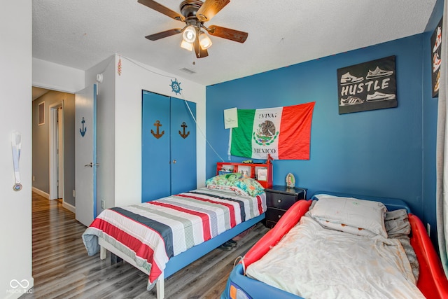 bedroom with wood-type flooring, a textured ceiling, ceiling fan, and a closet