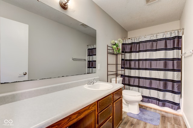 bathroom with a shower with shower curtain, vanity, wood-type flooring, a textured ceiling, and toilet