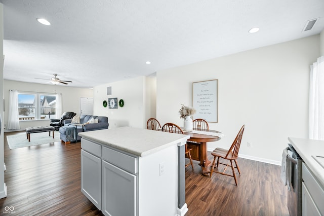 kitchen with dark wood-type flooring, a textured ceiling, dishwasher, a kitchen island, and ceiling fan