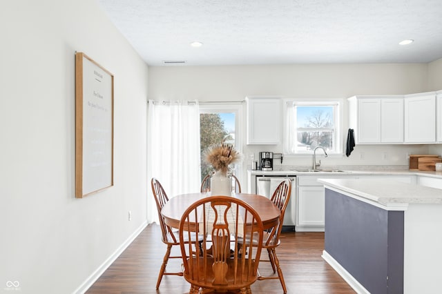 kitchen with sink, white cabinetry, dark hardwood / wood-style floors, a kitchen island, and stainless steel dishwasher