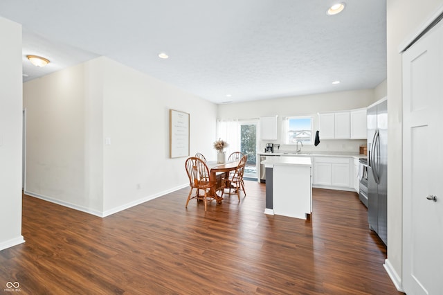 kitchen with dark wood-type flooring, a center island, a textured ceiling, stainless steel appliances, and white cabinets