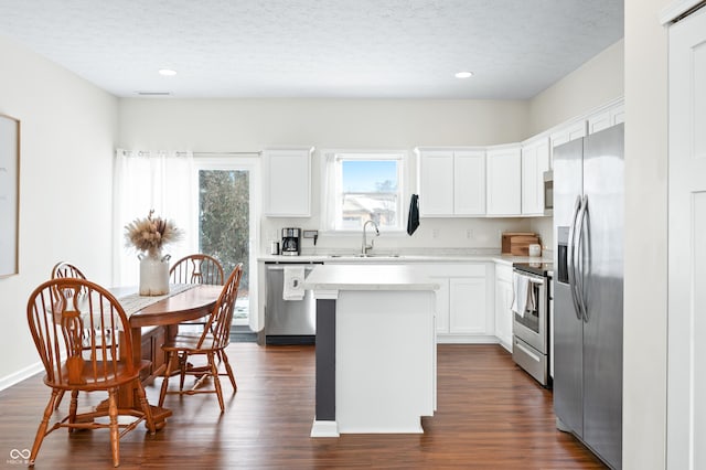 kitchen featuring sink, dark hardwood / wood-style flooring, a kitchen island, stainless steel appliances, and white cabinets