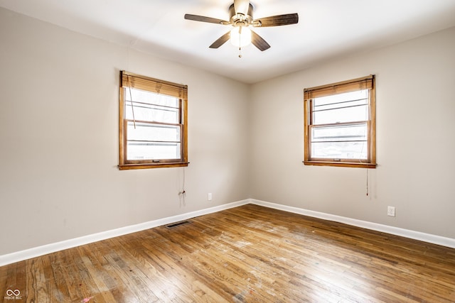 empty room with hardwood / wood-style floors, a wealth of natural light, and ceiling fan