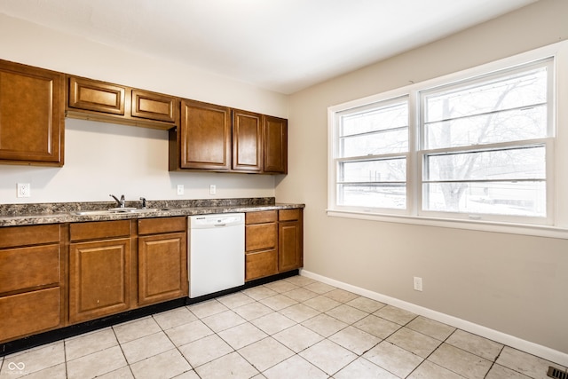 kitchen featuring white dishwasher, sink, and light tile patterned floors