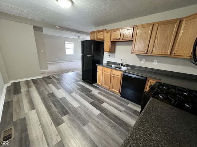 kitchen featuring black appliances, a textured ceiling, light wood-type flooring, sink, and ceiling fan