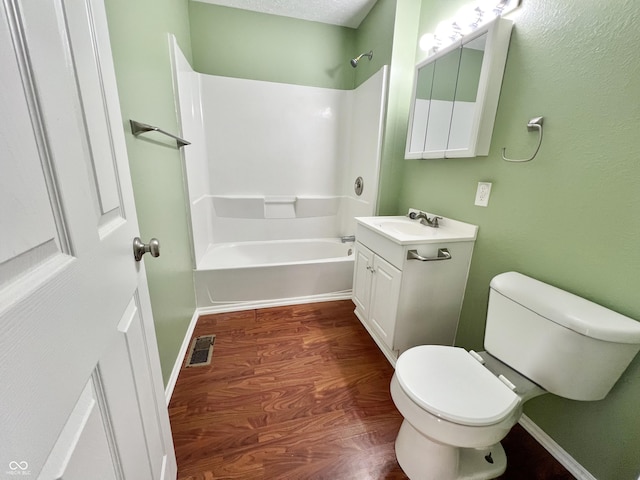 full bathroom with tub / shower combination, hardwood / wood-style floors, toilet, a textured ceiling, and vanity