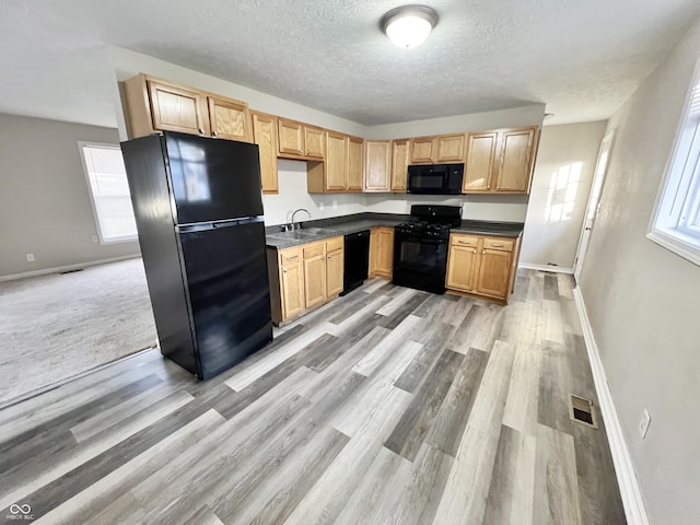 kitchen with light hardwood / wood-style flooring, light brown cabinetry, sink, a textured ceiling, and black appliances