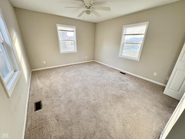 spare room with ceiling fan, plenty of natural light, and carpet