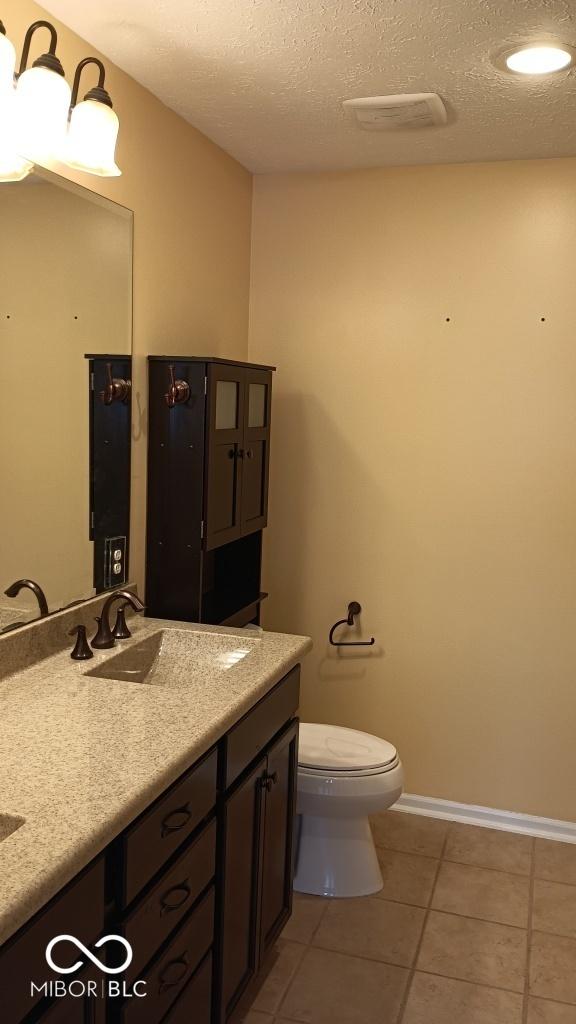 bathroom featuring a textured ceiling, tile patterned floors, vanity, and toilet