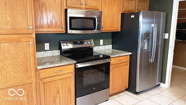 kitchen with light stone counters, light tile patterned floors, and appliances with stainless steel finishes