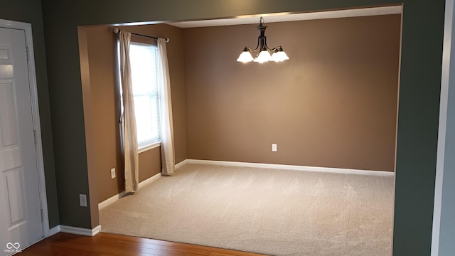 spare room featuring wood-type flooring and a notable chandelier