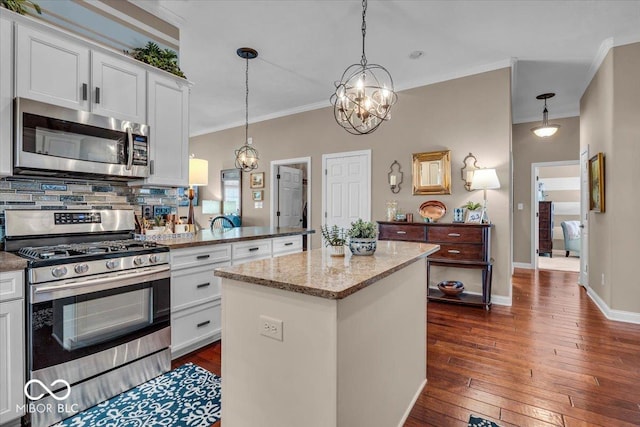 kitchen featuring a center island, stainless steel appliances, white cabinetry, and decorative light fixtures