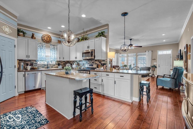 kitchen with a kitchen breakfast bar, pendant lighting, a center island, and appliances with stainless steel finishes