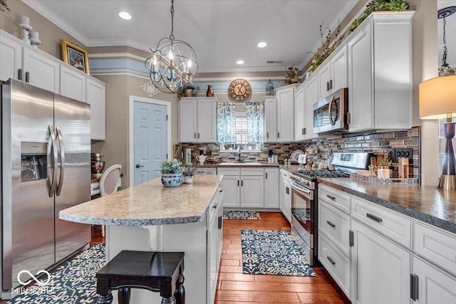 kitchen with pendant lighting, a breakfast bar area, decorative backsplash, and appliances with stainless steel finishes