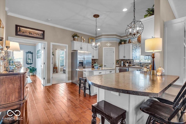 kitchen featuring white cabinets, a center island, hanging light fixtures, and appliances with stainless steel finishes