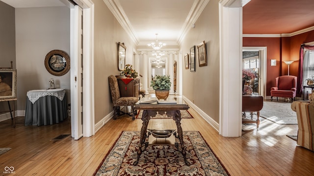 hall with light hardwood / wood-style flooring, crown molding, and a notable chandelier