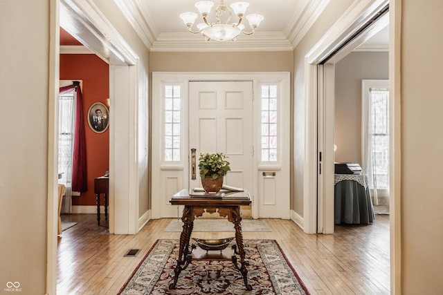 foyer featuring crown molding, an inviting chandelier, and light hardwood / wood-style flooring