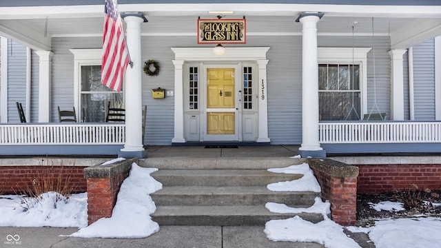 snow covered property entrance with a porch