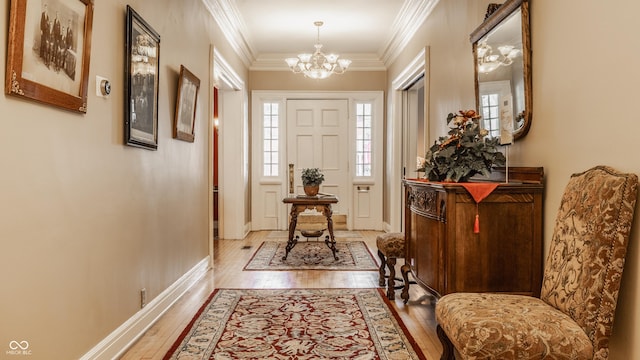 doorway with a chandelier, light hardwood / wood-style flooring, and ornamental molding