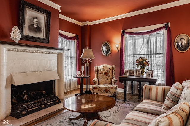 living area featuring a brick fireplace, crown molding, baseboards, and wood finished floors