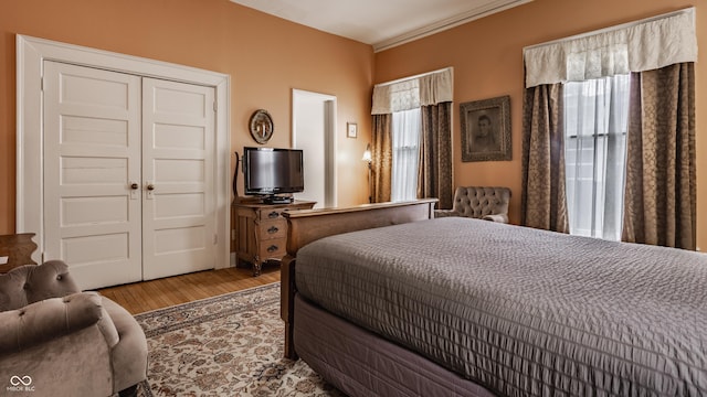 bedroom with wood finished floors, a closet, and ornamental molding