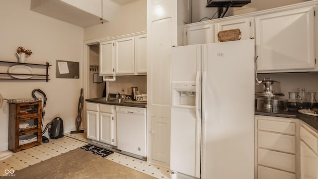 kitchen featuring dark countertops, light floors, white appliances, and a sink