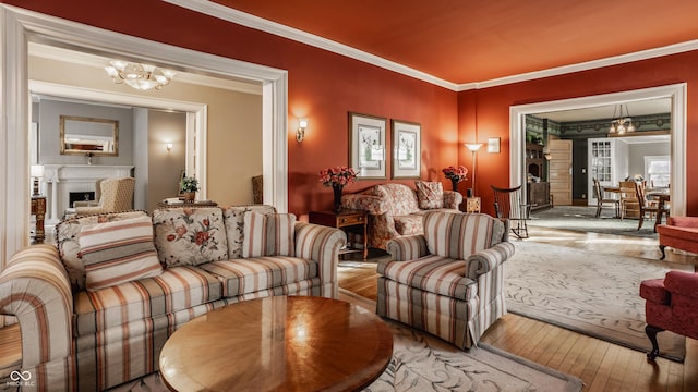 living room with hardwood / wood-style floors, an inviting chandelier, crown molding, and a fireplace