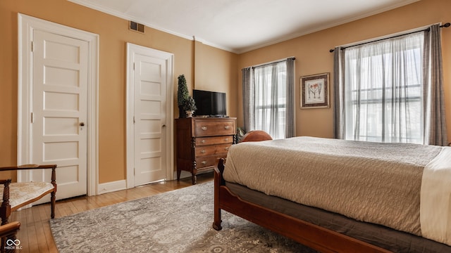 bedroom with hardwood / wood-style flooring, multiple windows, and ornamental molding