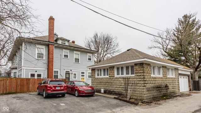 view of front of house with a garage, roof with shingles, and fence