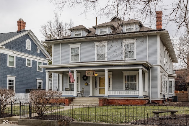 traditional style home featuring a fenced front yard, central air condition unit, covered porch, and a front lawn