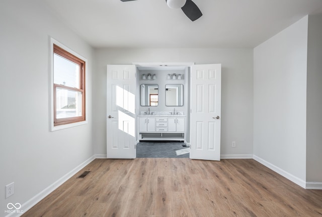 unfurnished bedroom with ceiling fan, ensuite bathroom, sink, and hardwood / wood-style floors