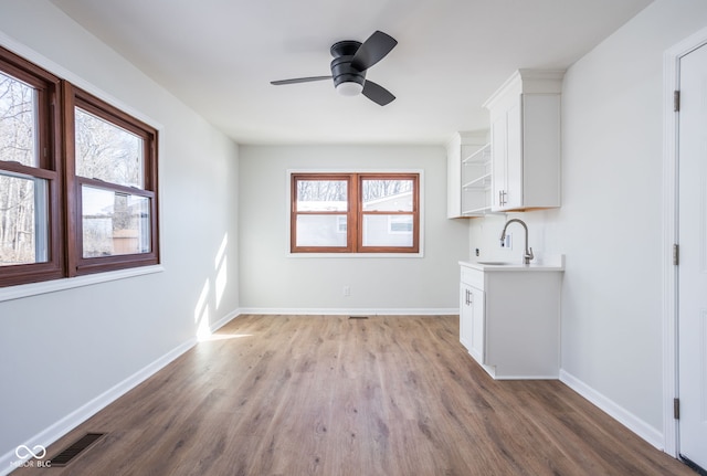 interior space with sink, ceiling fan, and light wood-type flooring