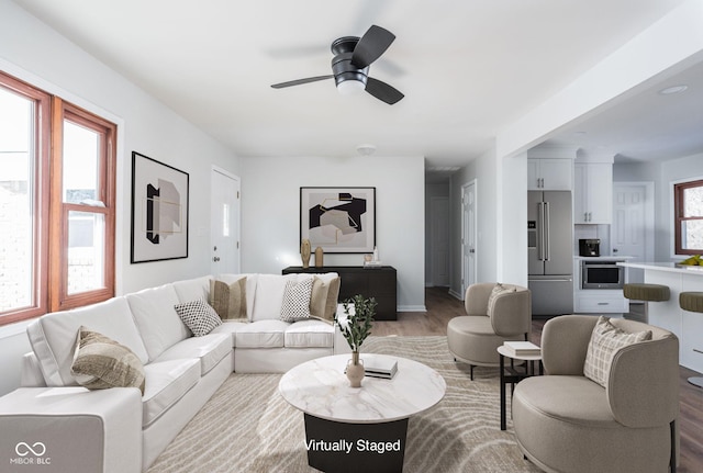 living room with plenty of natural light, ceiling fan, and light wood-type flooring